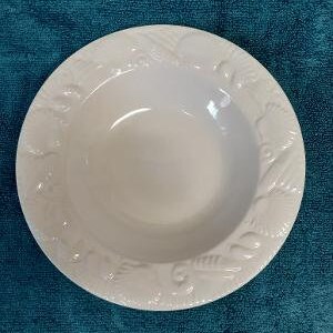 May include: White ceramic bowl with a raised floral design around the rim.