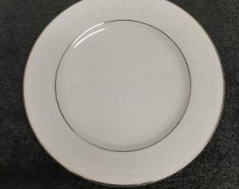 Può includere: Un piatto da portata in ceramica bianca con un bordo dorato e un delicato motivo floreale.