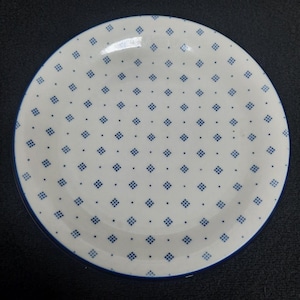 May include: A white ceramic plate with a blue diamond pattern and a blue rim.