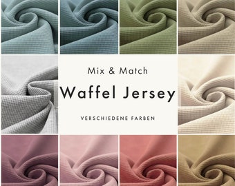 May include: A collection of waffle knit fabric swatches in various colours, including light blue, green, beige, grey, pink, red, and brown. The fabric is shown in a folded and twisted pattern. The text "Mix & Match Waffle Jersey VERSCHIEDENE FARBEN" is displayed in the centre of the image.