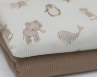 May include: Two stacks of ribbed fabric. The top layer is off-white and features a repeating pattern of light brown animal illustrations, including an elephant, whale, and penguin. The bottom layer is a solid, warm brown color.