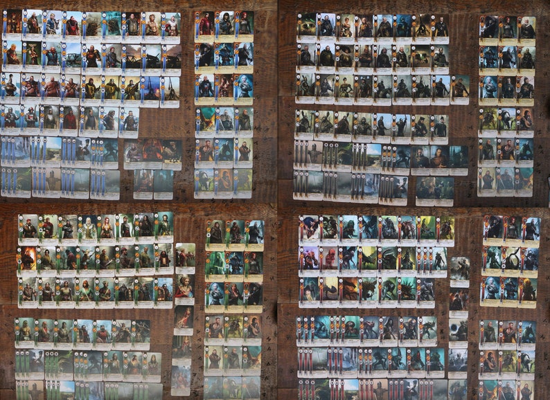 May include: A collection of trading cards featuring various characters and scenes, arranged on a wooden surface. The cards display detailed illustrations and are organized in multiple stacks and rows, showcasing a variety of fantasy-themed artwork.