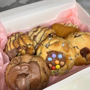 May include: A gift box filled with assorted cookies. The cookies include chocolate chip, chocolate chunk, and a cookie with colourful candy sprinkles.