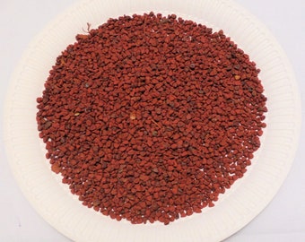 May include: A white plate filled with a large pile of small, red annatto seeds.