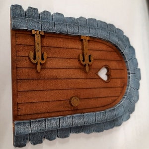 Une porte féerique avec un cadre en pierre et une fenêtre en forme de cœur.