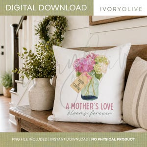 Op de afbeelding: Wit sierkussen met een aquarel bloemenontwerp in een glazen pot. Het kussen heeft roze en groene hortensia's, een label met "Emma & Carter" en de tekst "A Mother's Love blooms forever."