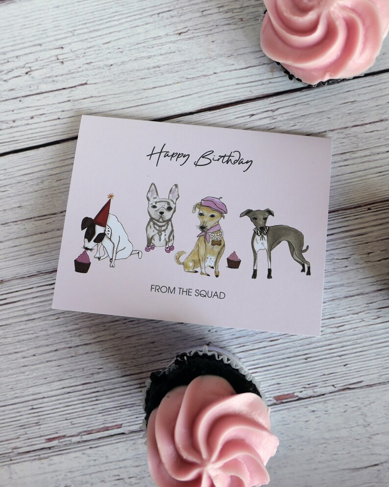 May include: A pink birthday card with a happy birthday message and four dogs wearing hats and holding cupcakes. The card says "From the Squad" at the bottom.