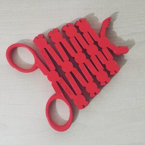 May include: Red plastic scissor shears with the words "SHEARS" and "SCISSOR" printed on the handles.