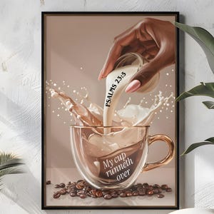May include: A framed art print depicts a hand pouring liquid into a clear coffee cup, creating a splash effect. The cup is filled with coffee beans and the text "My cup runneth over." The text "Psalms 23:5" is also visible.