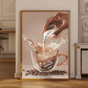 Può includere: Una stampa incorniciata raffigura una mano che versa un liquido cremoso in una tazza da caffè trasparente. La tazza è piena di caffè e le parole "My cup runneth over" sono visibili. L'immagine include chicchi di caffè e il testo "Psalms 23:5".