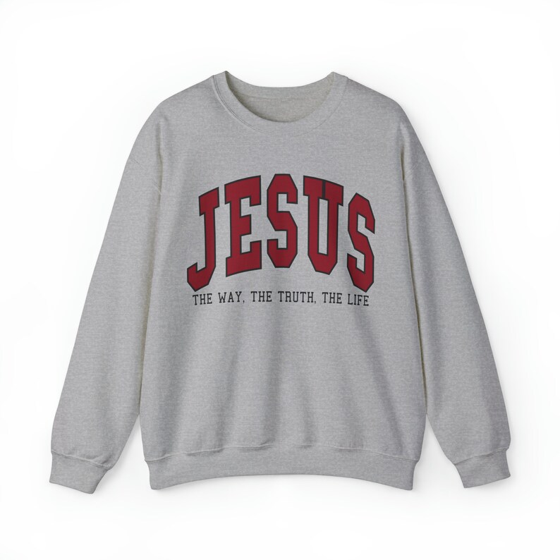 Może przedstawiać: Szara bluza z czerwonym nadrukiem "JESUS" w stylu uniwersyteckim. Pod nadrukiem znajduje się tekst "THE WAY. THE TRUTH. THE LIFE".