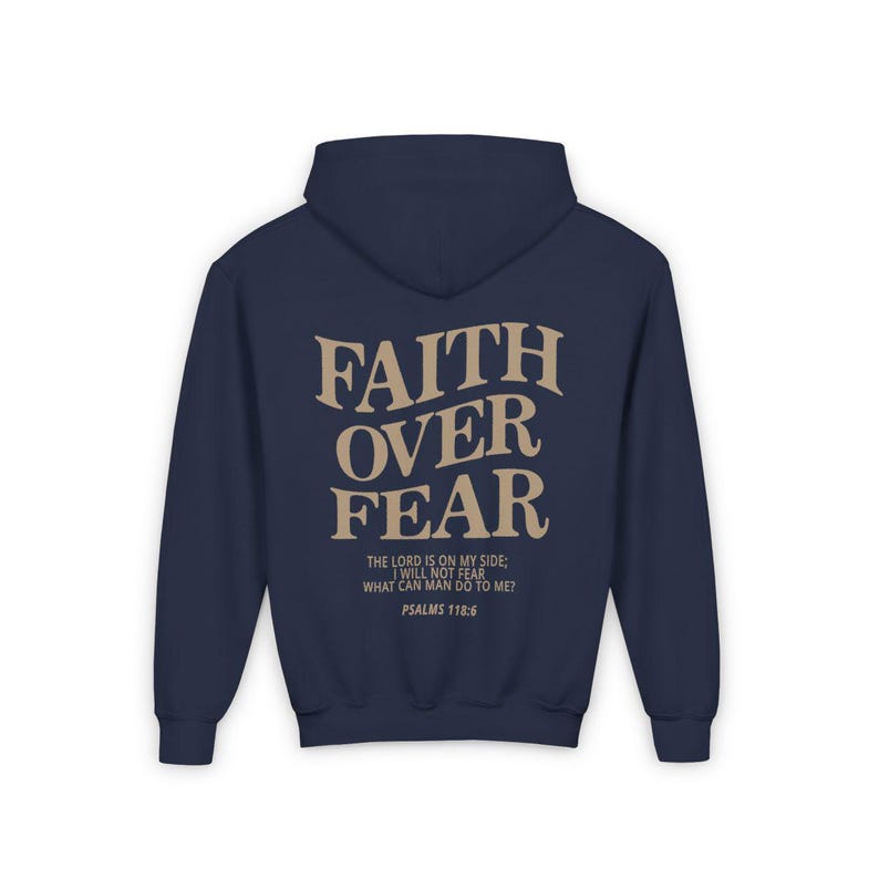 Puede incluir: Sudadera con capucha azul marino con una impresi&oacute;n en color tostado que dice "FAITH OVER FEAR" y la escritura "El Se&ntilde;or es mi ayuda, no temer&eacute;. &iquest;Qu&eacute; me puede hacer el hombre? Salmos 118:6"