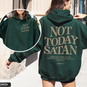 May include: Forest green hooded sweatshirt with the text "NOT TODAY SATAN" in tan lettering on the back. The text "THEREFORE SUBMIT TO GOD. RESIST THE DEVIL AND HE WILL FLEE FROM YOU. JAMES 4:7" is also printed in tan lettering on the back.
