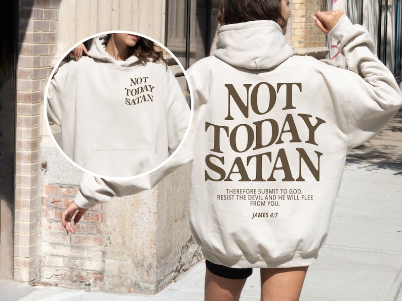 May include: A cream-colored hoodie with the text "NOT TODAY SATAN" in brown lettering. The text "THEREFORE SUBMIT TO GOD. RESIST THE DEVIL AND HE WILL FLEE FROM YOU. JAMES 4:7" is printed in smaller brown lettering below the main text.