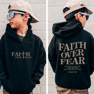 Puede incluir: Sudadera con capucha negra con el texto "FAITH OVER FEAR" en letras doradas en la parte delantera y trasera. La parte trasera tambi&eacute;n incluye el texto "THE LORD IS ON MY SIDE: I WILL NOT FEAR WHAT CAN MAN DO TO ME? PSALMS 118" en letras doradas m&aacute;s peque&ntilde;as.
