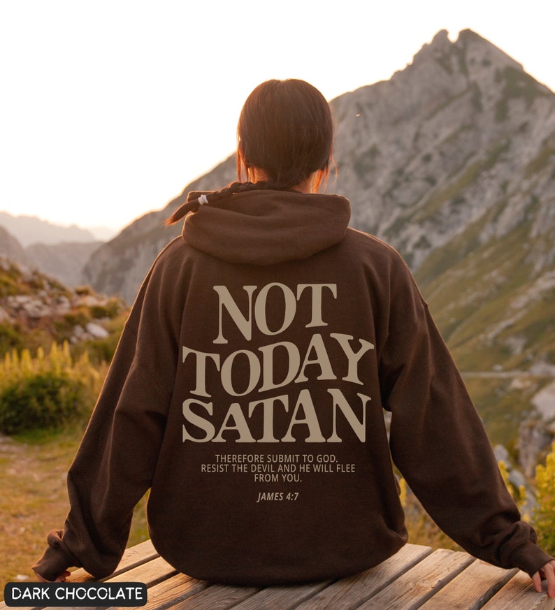 May include: A brown hoodie with the text "NOT TODAY SATAN" in beige lettering. The hoodie also features the text "THEREFORE SUBMIT TO GOD. RESIST THE DEVIL AND HE WILL FLEE FROM YOU. JAMES 4:7" in smaller beige lettering.