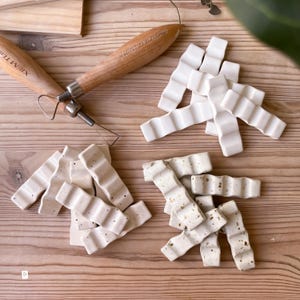 May include: Two sets of white ceramic tiles with a wavy design. One set has a speckled finish, while the other is smooth. The tiles are arranged in a random pattern.