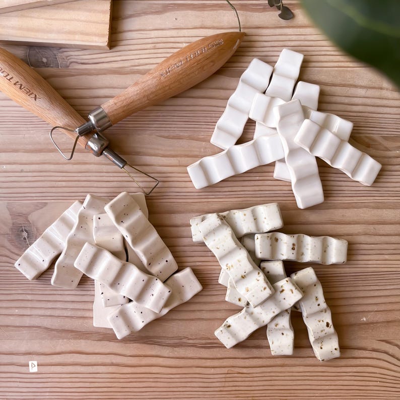 May include: Two sets of white ceramic tiles with a wavy design. One set has a speckled finish, while the other is smooth. The tiles are arranged in a random pattern.