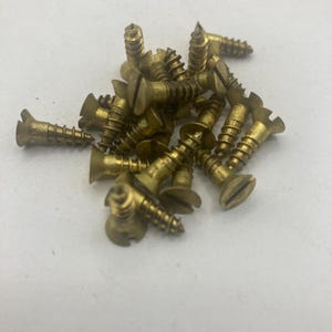 May include: A pile of brass screws with a flat head and a slotted drive. The screws are all the same size and have a shiny finish.
