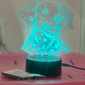 May include: A teal blue night light shaped like a Dalmatian dog with black spots. The light is on a black base and has a cord.