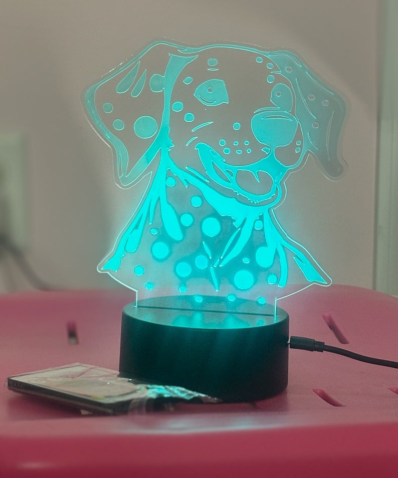 May include: A teal blue night light shaped like a Dalmatian dog with black spots. The light is on a black base and has a cord.