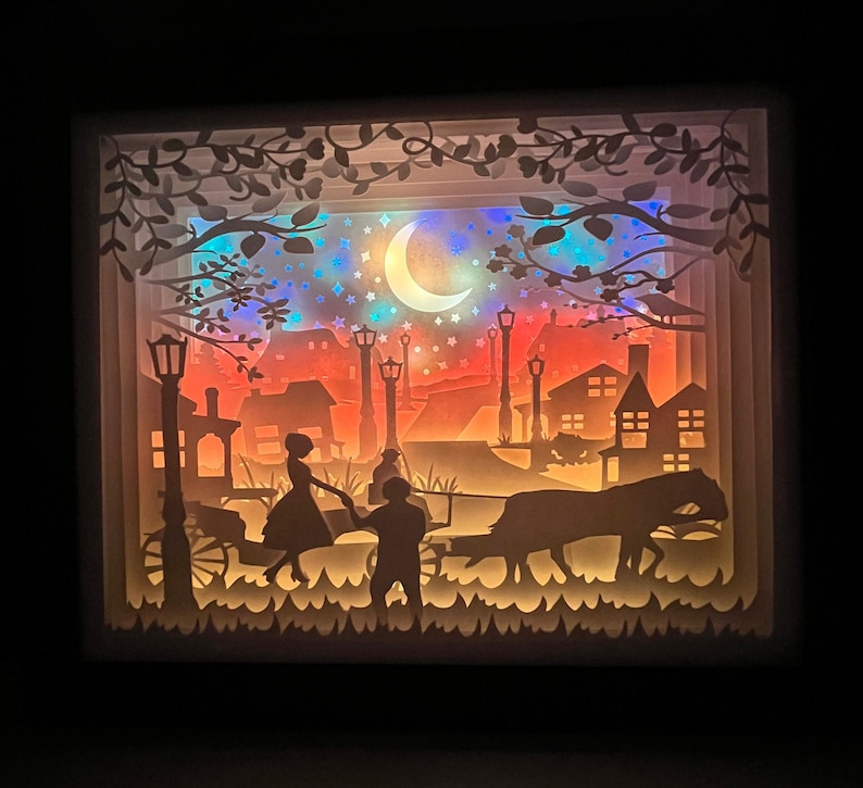 K&ouml;nnte beinhalten: Ein Papier-Schnittbild, das ein Paar zeigt, das Hand in Hand unter einem Halbmond geht. Die Szene spielt in einer Stadt mit Stra&szlig;enlaternen und Geb&auml;uden. Das Paar ist vor einem bunten Hintergrund silhouettiert.
