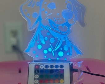 Puede incluir: Una luz nocturna de perro dálmata azul y blanco con un mando a distancia para cambiar el color de la luz. El mando a distancia tiene 16 opciones de color diferentes.