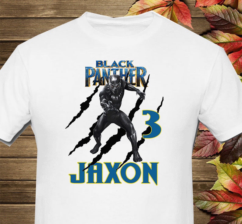 May include: White t-shirt with a black and gold "Black Panther" graphic, a black panther character, and the text "Jaxon" and "3" in blue.