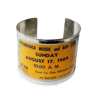 Entry ticket to the 1969 Woodstock Festival on a 4.5 cm wide bracelet. Made with recycled cans. Personalized internal text.