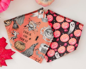 Puede incluir: Dos bandanas de tela con temática de Halloween. Una es naranja con una ilustración en blanco y negro de un cuervo, un esqueleto y el texto "Trick or Treat". La otra es negra con un fantasma blanco y calabazas naranjas.