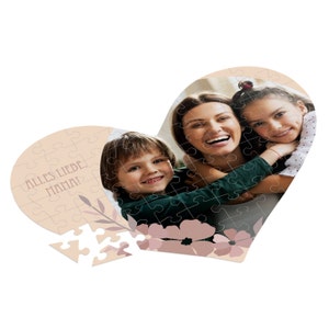 Pode incluir: Um quebra-cabeça em forma de coração com uma foto de uma mãe e seus dois filhos. O quebra-cabeça está parcialmente montado e apresenta um design floral com o texto "Alles Liebe, Mama!" no lado esquerdo.