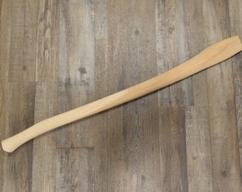 May include: A wooden axe handle with a natural finish. The handle is smooth and has a slight curve.
