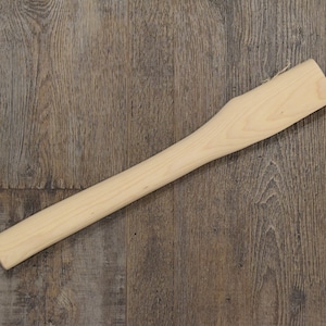 May include: A plain wooden axe handle, light brown in color, with a slightly rounded end.