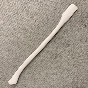 May include: A light-colored wooden axe handle. The handle is a pale, natural wood color and has a curved design for a comfortable grip. The handle is smooth and appears to be unfinished, ready for use or customization.