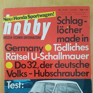 May include: A red and white magazine cover with the title "hobby" and a picture of a white Hillman Imp car. The text on the cover reads "Neu: Honda Sportwagen!" and "Hillman Imp-Schlager oder Versager?"