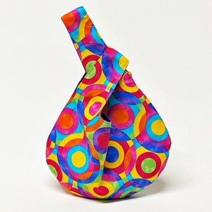 May include: A colorful tote bag with a geometric pattern of overlapping circles in shades of pink, blue, yellow, green, and orange.