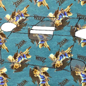 May include: A black and white illustration of a video game console with a blue and white background pattern featuring the words "Zelda: Breath of the Wild".