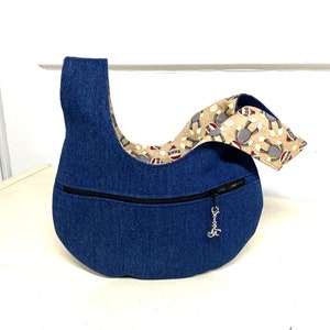 May include: A blue denim hobo bag with a zippered pocket and a monkey print fabric lining. The bag has a silver charm attached to the zipper.