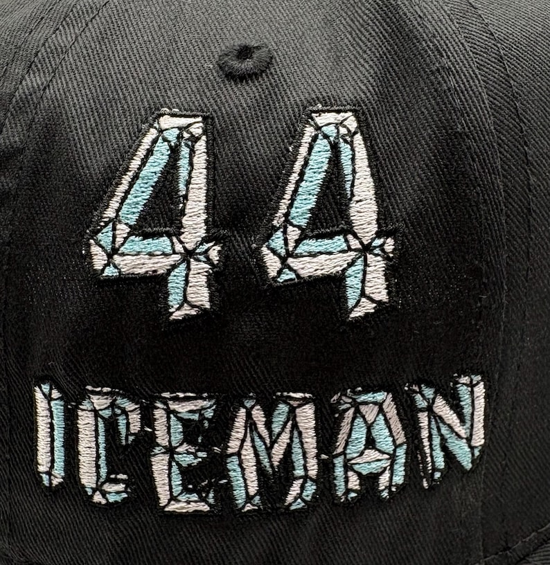 May include: Black baseball cap with the number "44" and the word "ICEMAN" embroidered in a light blue and white diamond pattern. The cap is made of a textured fabric.