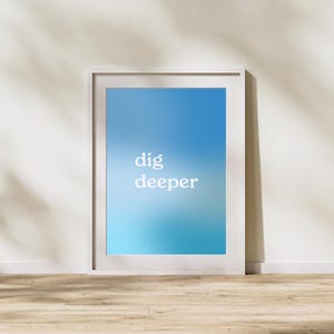 Op de afbeelding: Witte ingelijste poster met een blauwe gradiënt achtergrond en de tekst "dig deeper" in wit.