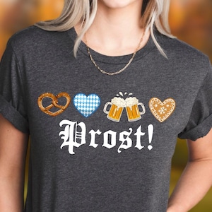 A woman wearing a gray t-shirt with the text "Prost!" printed on it, along with images of pretzels, beer mugs, and hearts.