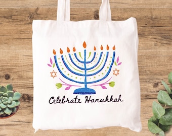 May include: White canvas tote bag with a blue and white menorah design and the text "Celebrate Hanukkah".