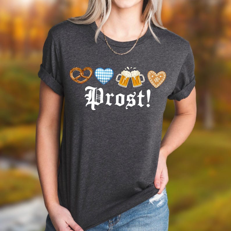 A woman wearing a gray t-shirt with the text "Prost!" printed on it, along with images of pretzels, beer mugs, and hearts.
