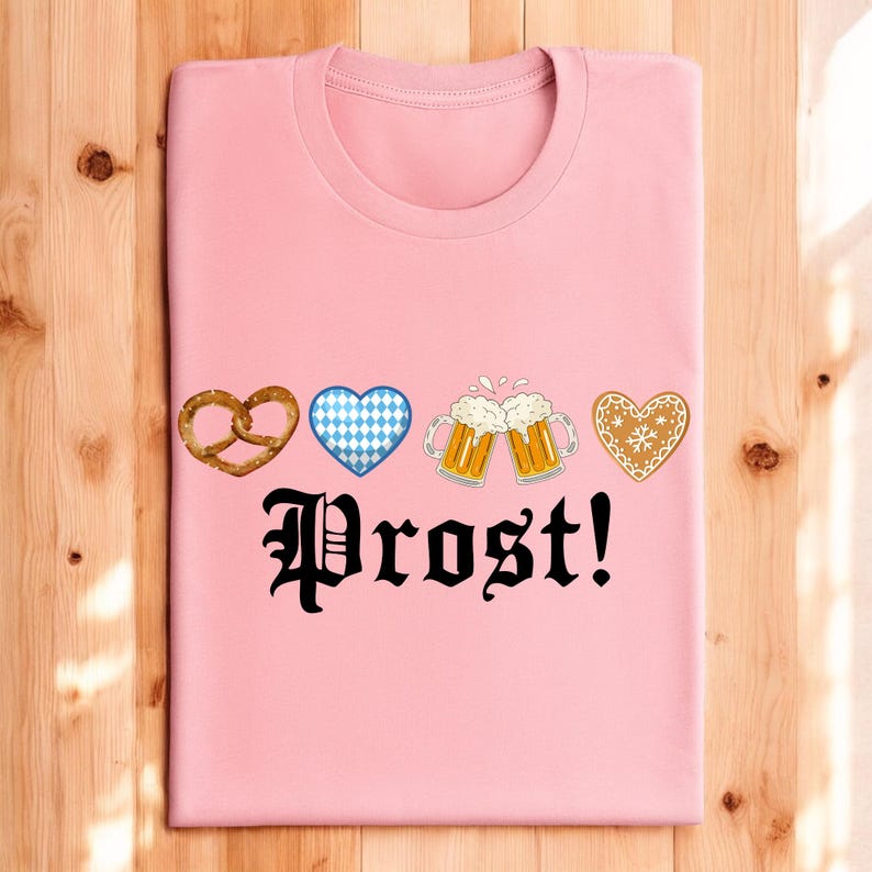 A pink t-shirt with the text "Prost!" printed on it, along with four heart-shaped icons representing pretzels, beer mugs, and gingerbread cookies.