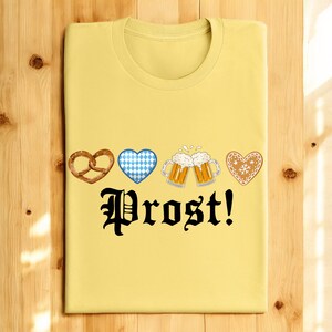 A yellow t-shirt with a graphic design featuring four heart-shaped icons and beer mugs, along with the text "Prost!"