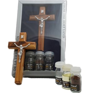 May include: A set of religious items from the Holy Land, including a wooden crucifix, olive oil, earth from Bethlehem, and water from the Jordan River. The items are packaged in a clear plastic box with the text "From the Holy Land" printed on the side.