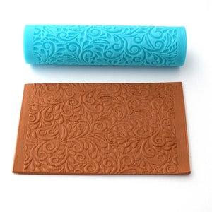 May include: A blue silicone rolling pin with a decorative swirl pattern and a brown silicone mat with the same pattern.