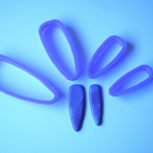 May include: Five purple plastic cookie cutters shaped like flower petals, with two smaller purple plastic cookie cutters in the center.