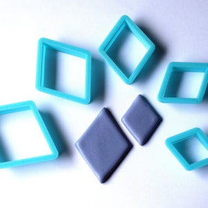 May include: A set of six blue diamond-shaped cookie cutters and two gray fondant diamonds.