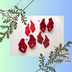 May include: Six red plastic earrings in the shape of a butterfly. The earrings are arranged in two groups of three, labeled A and B.
